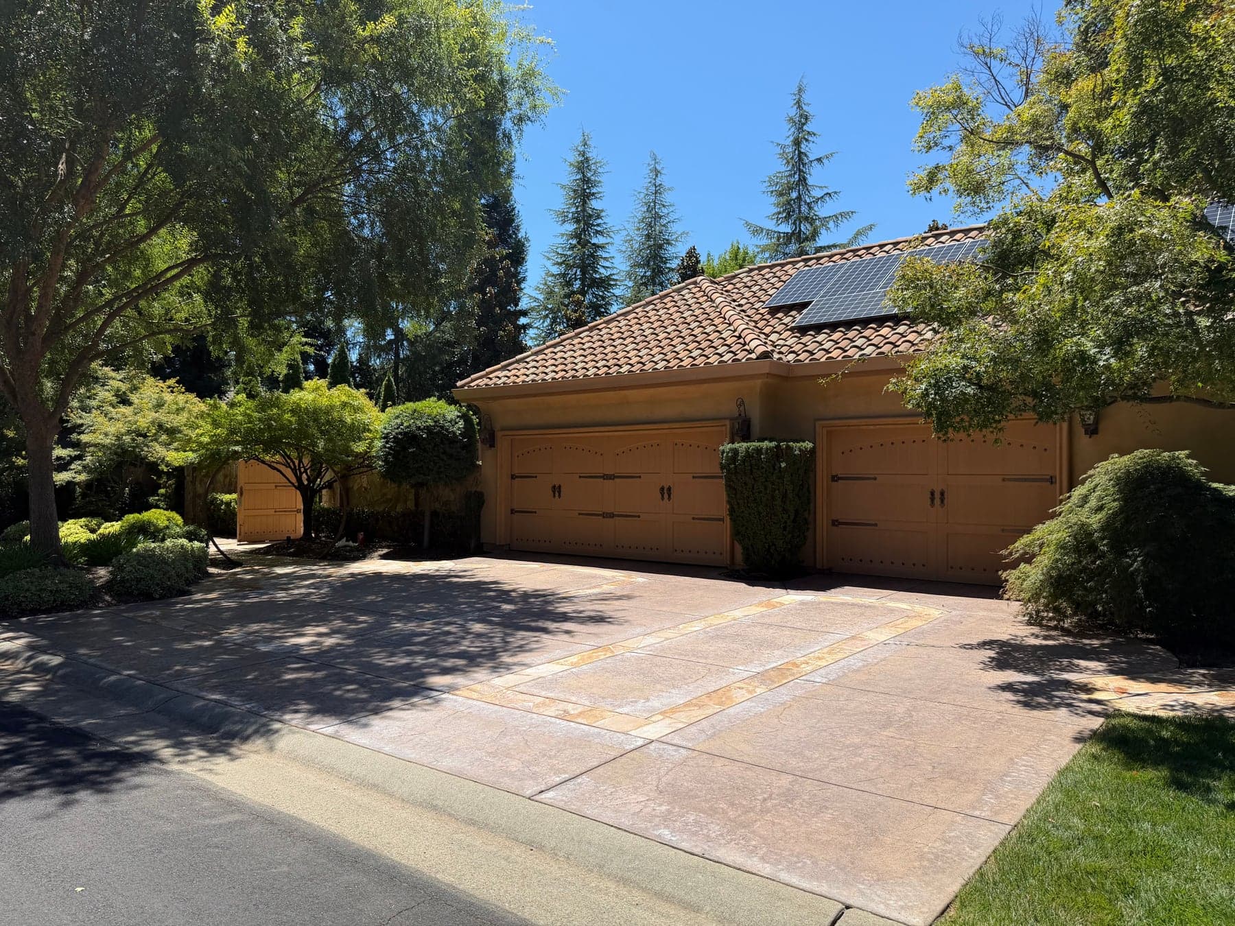 Stamped concrete driveway in front of a three-car garage after cleaning — even color across the surface, borders intact